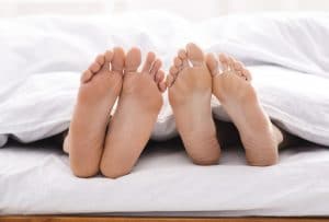 Feet of couple in bed under blanket