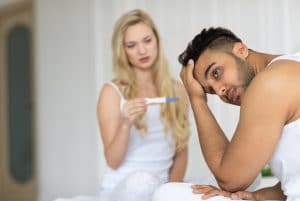 Young Couple Sitting In Bed, Woman Show Man Positive Pregnancy Test Conflict Relationships Problem